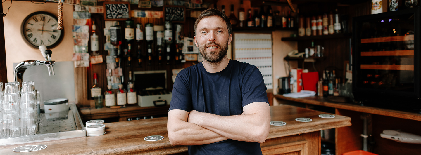 Cafe owner standing behind counter with arms crossed